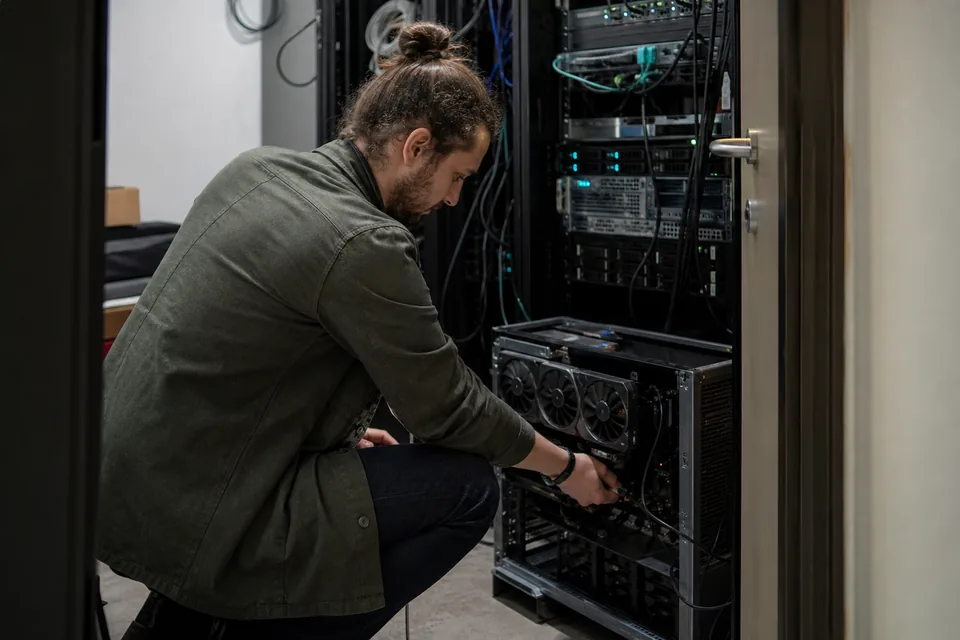 Engineer plugging cables into a GPU workstation tower in a small server closet